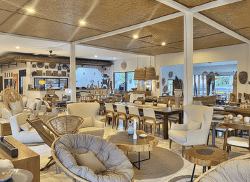 Spacious Bali furniture showroom interior displaying hand-crafted rattan lounge chairs, live-edge coffee tables, and dining sets.